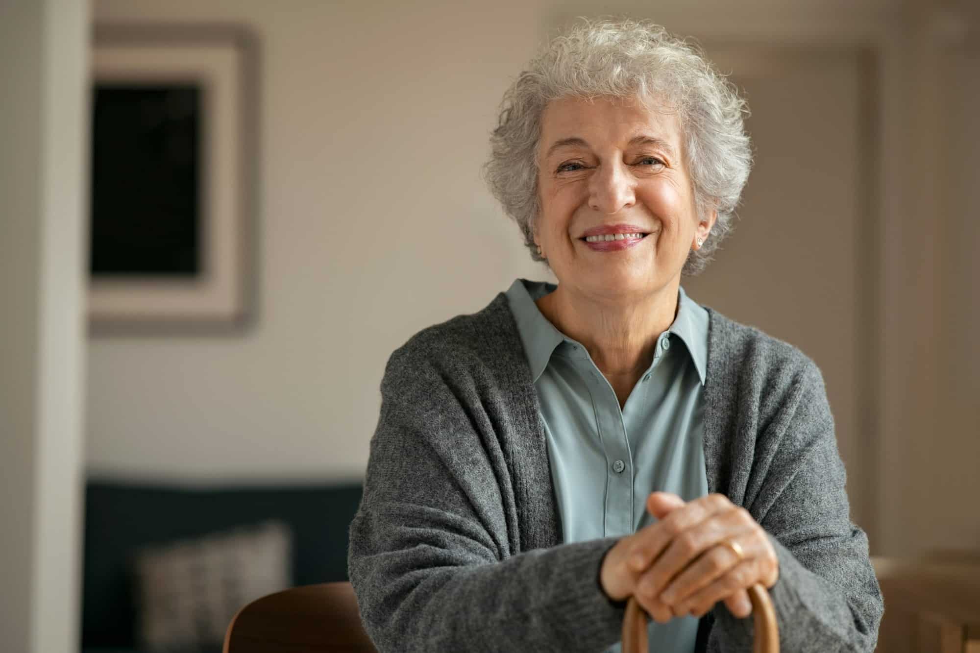 Smiling elderly woman looking at camera indoors