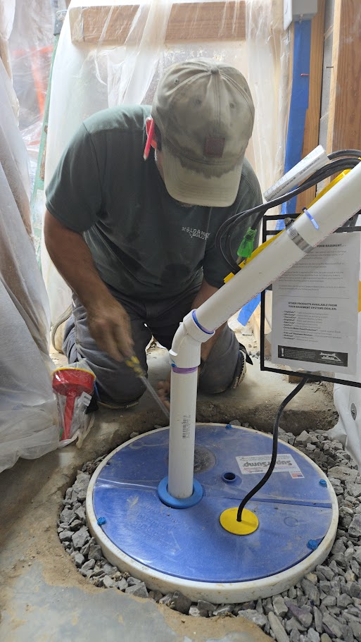 Technician installing a sump pump system in a basement.