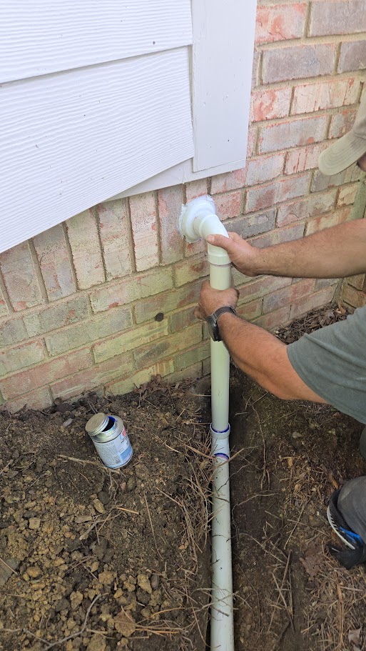 Technician fixing an exterior pipe for water damage repair.