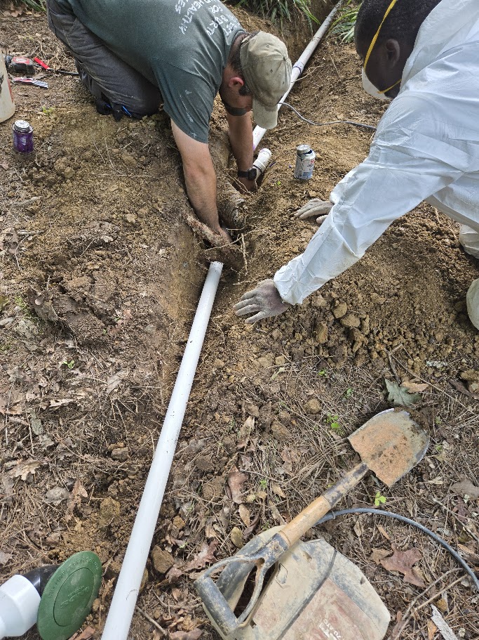 Technicians installing a pipe in a trench for water control