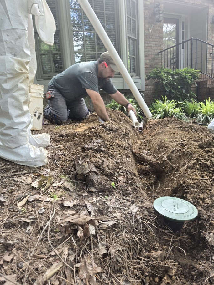 Technician installing pipes for drainage in a garden area.