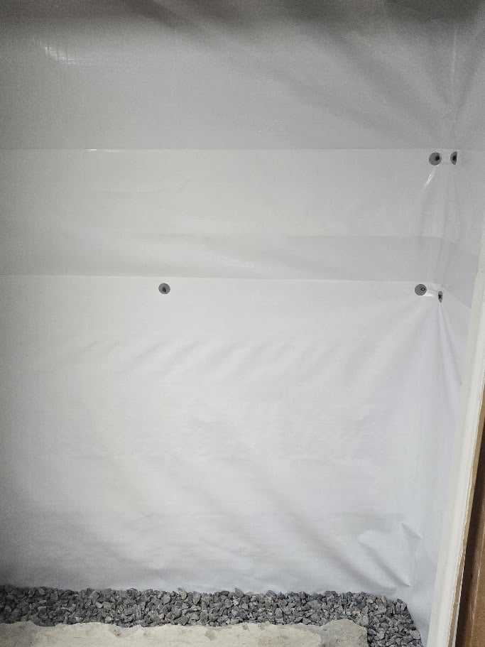 Basement wall covering for moisture prevention featuring white plastic sheeting.
