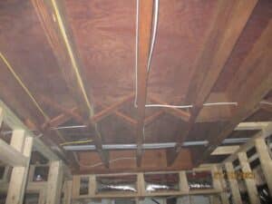 Exposed ceiling beams in a basement under renovation.